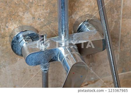 Dirty faucet with salt deposits from water in bathroom on marble modern dark tile. Cleanliness and cleaning. Caring for house and order. Lifestyle. Dirty faucet with salt deposits from water in bathroom on marble modern dark tile. Cleanliness and cleaning. Caring for house and order. Lifestyle. 123367985