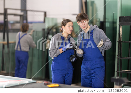 Young woman and young guy discussing work in glass factory 123368691
