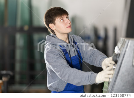Young man workshop employee switches toggle switch on control panel 123368774