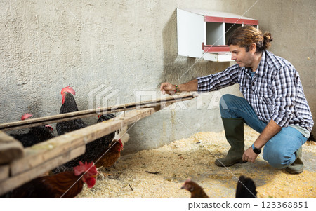 Male farmer feeding bird in the backyard of village house 123368851