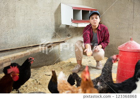 Young female farmer feeding hens 123368868