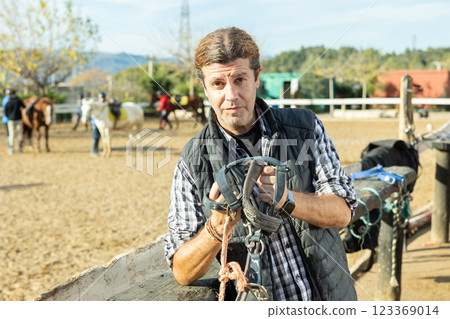 Owner of the stable poses in front of corral for horses 123369014