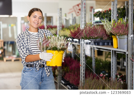 Young woman holding pot of heather in plant store Young woman holding pot of heather in plant store 123369083