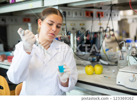 Female chemist working in laboratory, analyzing liquid samples in test flasks 123369162