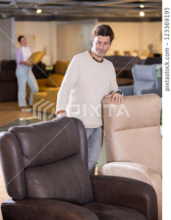 Man looking for armchair in furniture showroom Man looking for armchair in furniture showroom 123369195
