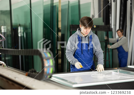 In workshop for production of glass products, guy co-worker cuts off excess from workpiece In workshop for production of glass products, guy co-worker cuts off excess from workpiece 123369238