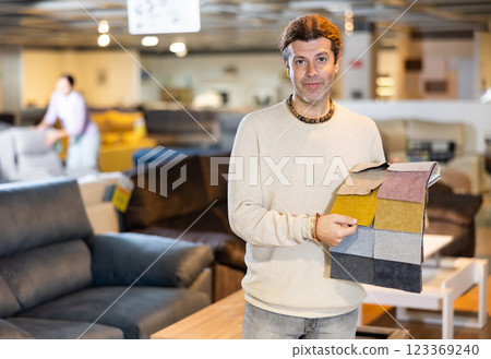 Male furniture salesman showing different fabric samples in furniture showroom Male furniture salesman showing different fabric samples in furniture showroom 123369240