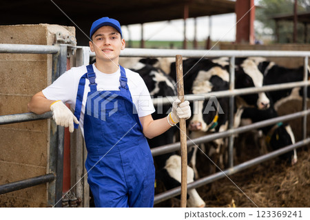 Portrait of positive male farm worker in cowshed 123369241