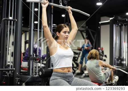 Woman is engaged in a simulator for development of back muscles Woman is engaged in a simulator for development of back muscles 123369293
