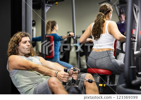 Caucasian man using cable row machine in gym Caucasian man using cable row machine in gym 123369399