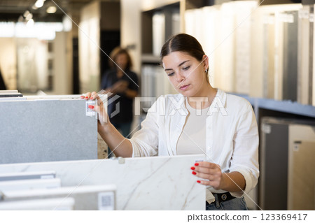Focused woman choosing wall tiling materials in hardware shop Focused woman choosing wall tiling materials in hardware shop 123369417