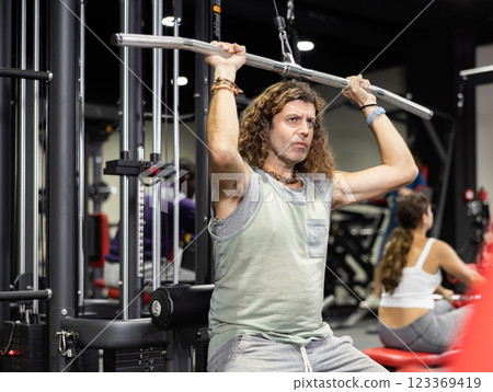 Caucasian sportsman doing reps on lat pull down machine in gym 123369419