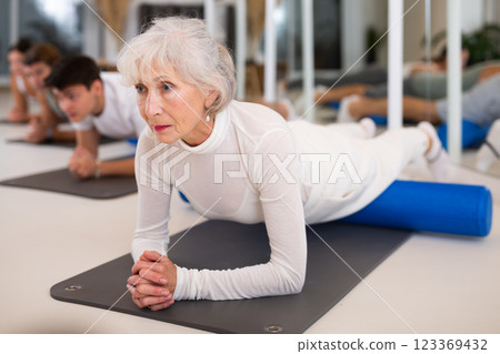 Elderly woman doing pilates with roller 123369432