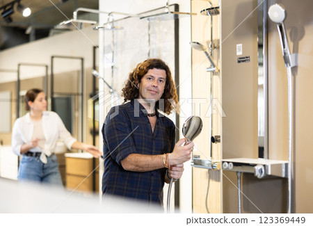 Handsome man choosing a shower head in hardware store Handsome man choosing a shower head in hardware store 123369449