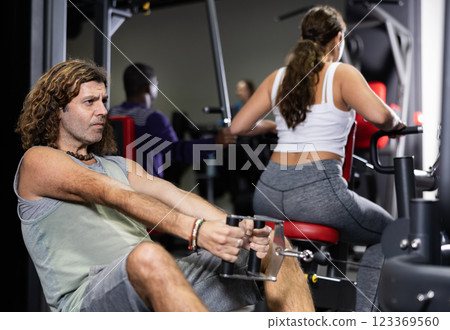Caucasian man is engaged in a simulator with horizontal weights in gym 123369560