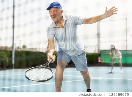 Portrait of aged man enjoying friendly tennis match at outdoors court Portrait of aged man enjoying friendly tennis match at outdoors court 123369679