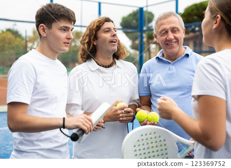 Group portrait of four padel players of different ages standing at tennis court at fitness health club 123369752