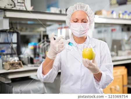 Female geneticist working in laboratory, injecting additives into apple during experiments with genetically modified apple 123369754