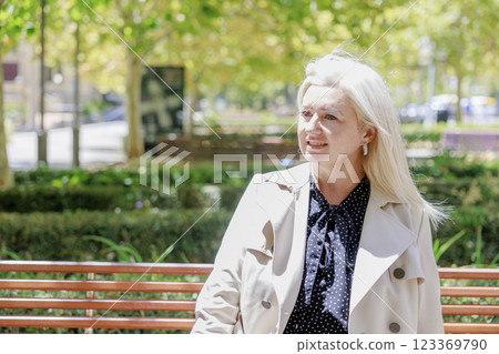 White-haired Caucasian woman sitting on a park bench White-haired Caucasian woman sitting on a park bench 123369790