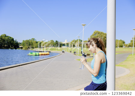 Woman after running drinking water in the park 123369842