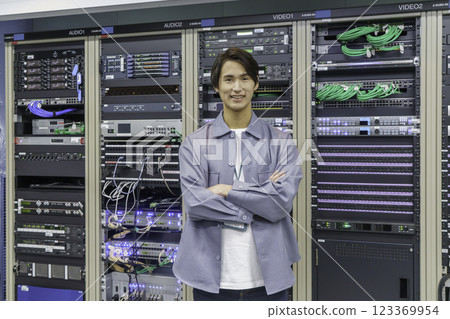 一名年輕人站在電視台控制室的設備前。 123369954