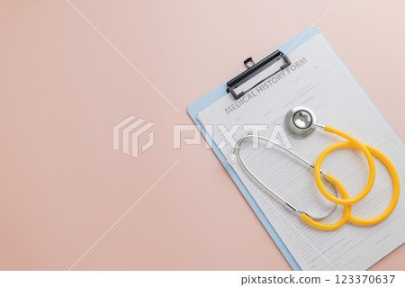 Doctor Day highlights a clipboard with a medical history form and yellow stethoscope on pink Doctor Day highlights a clipboard with a medical history form and yellow stethoscope on pink 123370637