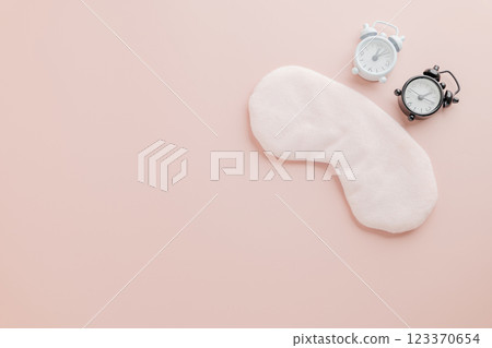 Stylish flat lay for World Sleep Day, eye mask and clock on pink background. 123370654