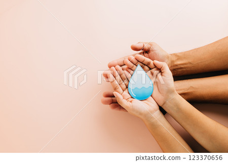 World Water Day highlights with two pairs of hands holding a blue water droplet. World Water Day highlights with two pairs of hands holding a blue water droplet. 123370656
