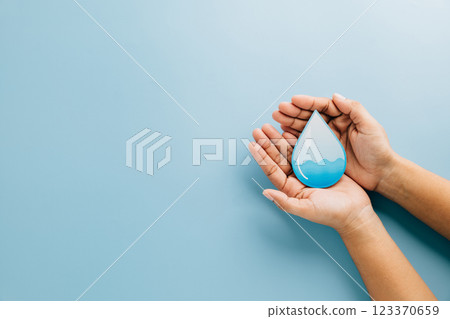 World Water Day. Hands hold water drop paper cut on blue background, symbolizing care, saving water 123370659