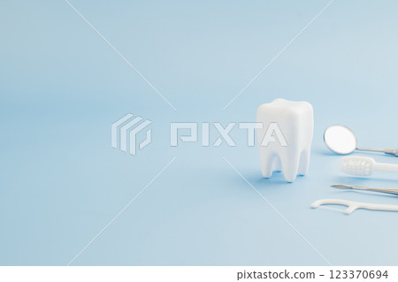Dentist focuses on health education using tools and a teeth model on blue background Dentist focuses on health education using tools and a teeth model on blue background 123370694