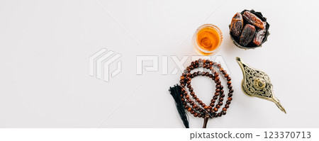 Overhead view of dates in a bowl, prayer beads, tea, and teapot for Ramadan. 123370713