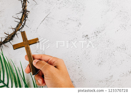 Hand holding cross and crown of thorns for Palm Sunday. Celebrating Easter faith Hand holding cross and crown of thorns for Palm Sunday. Celebrating Easter faith 123370728