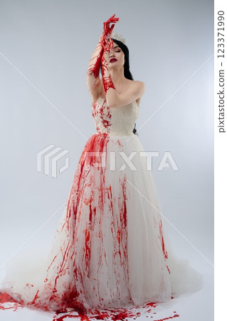 Bride in blood-soaked gown holding knife evokes a chilling beauty 123371990