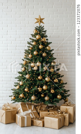Elegant Christmas tree decorated with gold ornaments and lights in front of a white brick wall. Perfect for minimalist holiday greetings Elegant Christmas tree decorated with gold ornaments and lights in front of a white brick wall. Perfect for minimalist holiday greetings 123372076