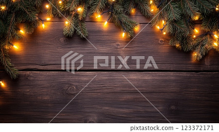 Overhead view of Christmas pine branches with lights draped across a wooden surface. Perfect for holiday backgrounds. 123372171
