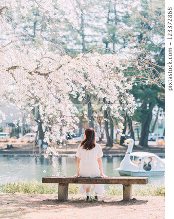 一名女子在春天的公園拍攝油菜花 一名女子在春天的公園拍攝油菜花 123372868