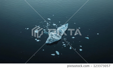 Aerial view of an iceberg and smaller pieces of ice floating on the surface of dark blue water, creating a serene and minimalist composition 123373057