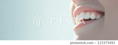 Close up of perfect smile with white teeth and beautiful pink lips of young woman smiling on light blue background representing beauty, cosmetology, dentistry, and healthcare 123373091