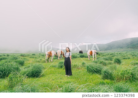 一名女子與一匹馬行走在熊本縣阿蘇市草千里的草原上 123374398