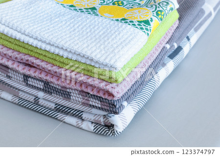 Clean after washing waffle kitchen towels, flannel plaid linens. Stacked pillowcases, duvet cover after ironing. Cleanliness and housekeeping.  123374797