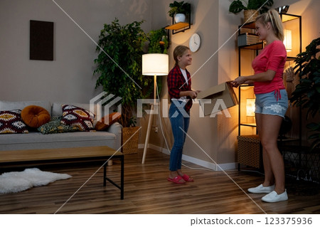 A Heartwarming Family Moment A Child Joyfully Receiving a Gift in a Cozy Living Room Setting 123375936
