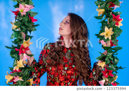 A Beautiful Woman Surrounded by Colorful Flowers Beautifully Set Against a Blue Background 123375994