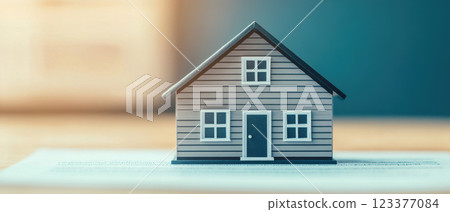 small model house sits on contract, symbolizing real estate transactions and home ownership. artistic blur effect adds creative touch to scene 123377084