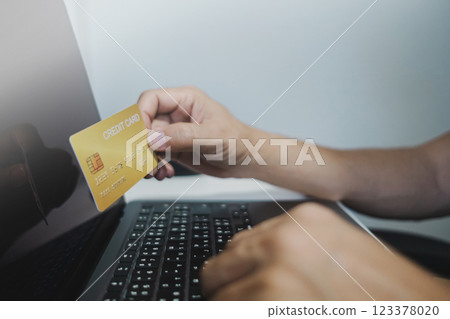 Close up, Man holding credit card while using laptop, shopping online, buying on internet. e-commerce e-banking service. 123378020