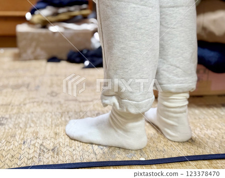 Feet of a person wearing sweatpants standing in a messy room 123378470
