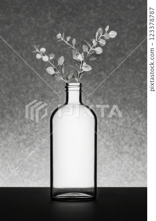 Minimalist glass bottle with delicate branches on a subtle backdrop 123378787