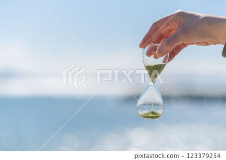 Person holding an hourglass on the beach 123379254