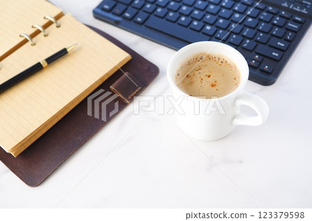 An image of a person working at a desk with a ring-type system organizer open, drinking coffee (cafe latte) and doing desk work at a computer 123379598