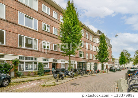 A scenic view of a residential street lined with trees and bicycles, showcasing urban living and greenery in a city environment. 123379992