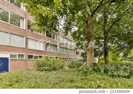 A contemporary building featuring large windows is accented by abundant greenery, creating a serene and inviting environment. 123380094